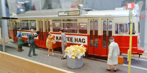 Vier Spielzeugfiguren stehen vor einer Miniatur-Straßenbahn