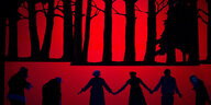 Schwarze Silhouetten von Menschen und Bäumen auf roter Leinwand