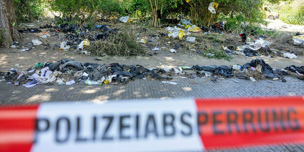 Wärmedecken, Kleidungsstücke und weiterer Müll liegen hinter einem Absperrband der Polizei am Alexis-Schumann-Platz in Leipzig