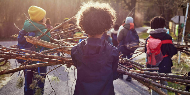 Kinder tragen Stöcke und Holz für ein Lagerfeuer zusammen