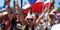 Ein Mann schwenkt eine polnische Fahne, eine Frau macht das Peace-Zeichen