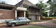 Ein schlichtes Haus in Afrika, mit einem Auto davor in den 70ern