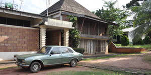 Ein schlichtes Haus in Afrika, mit einem Auto davor in den 70ern
