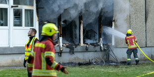 Die Feuerwehr löscht einen Brand in einer Flüchtlingsunterkunft