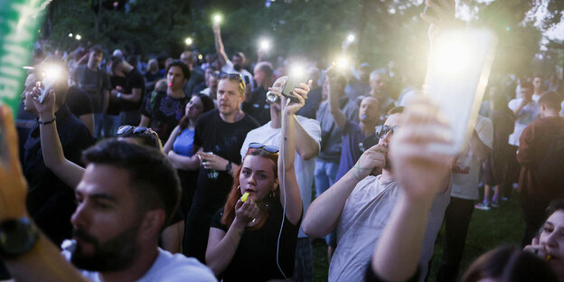 Menschen hlten ihre leuchtenden Smartphones in der Dämmerung in die Höhe