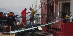 Eine Person, die sich mit goldener Rettungsfolie bedeckt hat verlässt ein Rettungsschiff