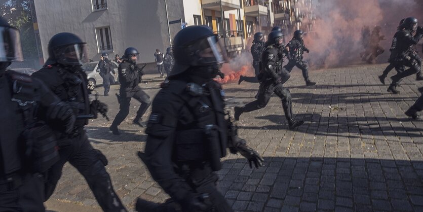 Uniformite Polizisten mit Schutzhelmen rennen durch eine Straße