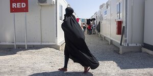 Eine Frau mit Niqab in einem Containerdorf