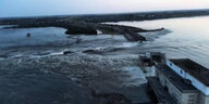 Luftbild des zerstörten Staudamms. Wassermassen fließen durch die kaputte Mauer.