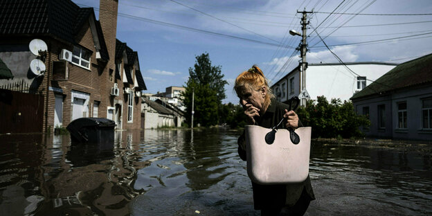 Eine Person watet durch eine überflutete Straße