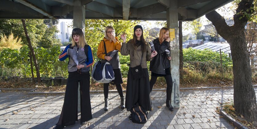 4 junge Frauen stehen unter einem Betondach und essen aus einer Papiertüte