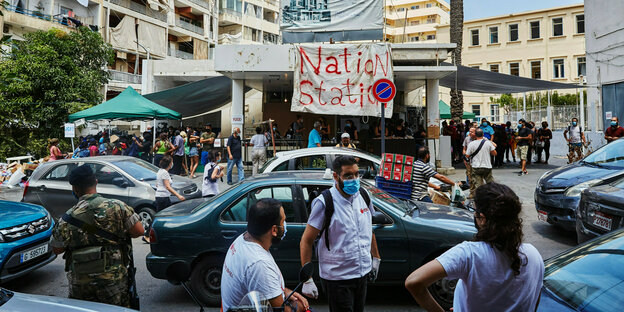 Eine Straße zeigt Autos und Menschen, und einen Banner worauf Nation Station steht