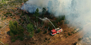 Ein Feuerwehraut spritz Wasser auf einen Waldbrand bei Jüterbog