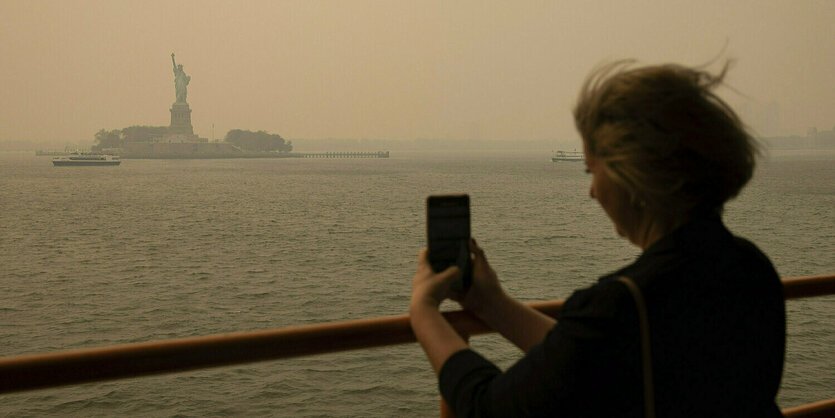 Eine Frau fotografiert die Freiheitsstatue im Nebel