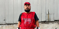 Pisitakun Kuantalaen in einem roten T-Shirt mit Tiger vor einer Wellblechwand
