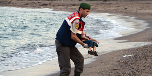 Ein Mann trägt den Leichnam eines syrischen Kindes.