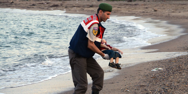 Ein Mann trägt den Leichnam eines syrischen Kindes.