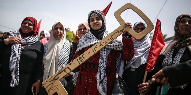 Frauen mit Palästinenser-Tüchern halten einen übergroßen SChlüssel
