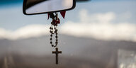 Ein Kreuz am Rückspiegel eines Autos