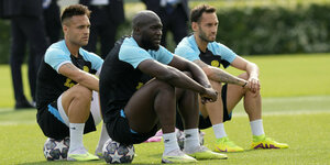 Lautaro Martinez, Hakan Calhanoglu und Romelu Lukaku sitzen beim Traing auf Bällen mit dem Champions-League-Logo