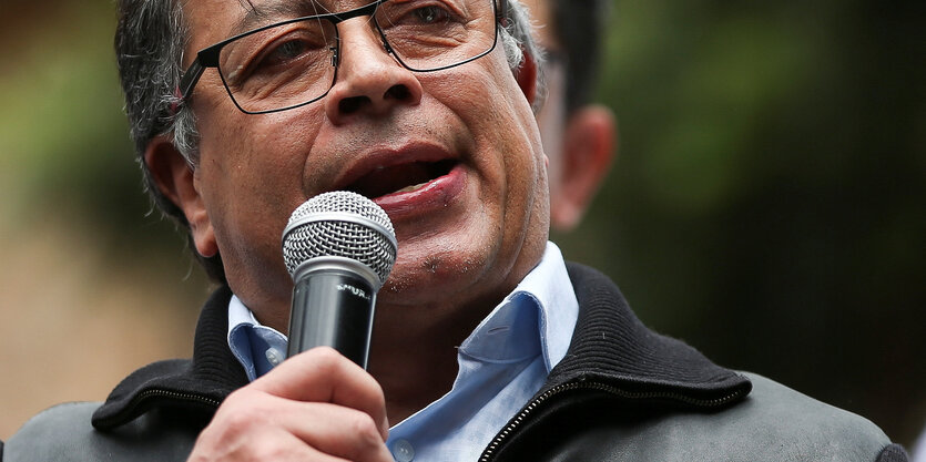 Gustavo Petro, ein mittelalter Weißer Mann mit Brille, spricht in ein Mikrophon