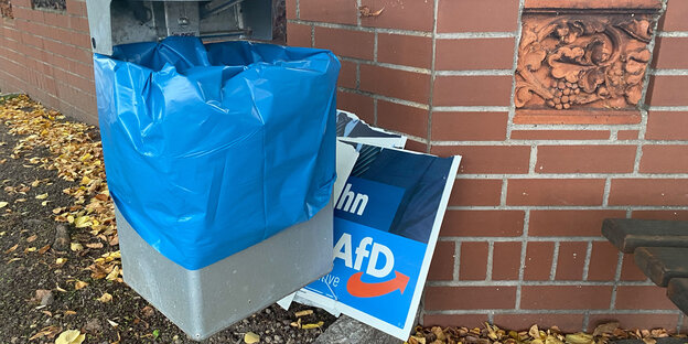 Ein offenbar mutwillig zerstörtes Wahlplakat der AfD zur Landtagswahl 2022 in Niedersachsen steht neben einem Mülleimer.