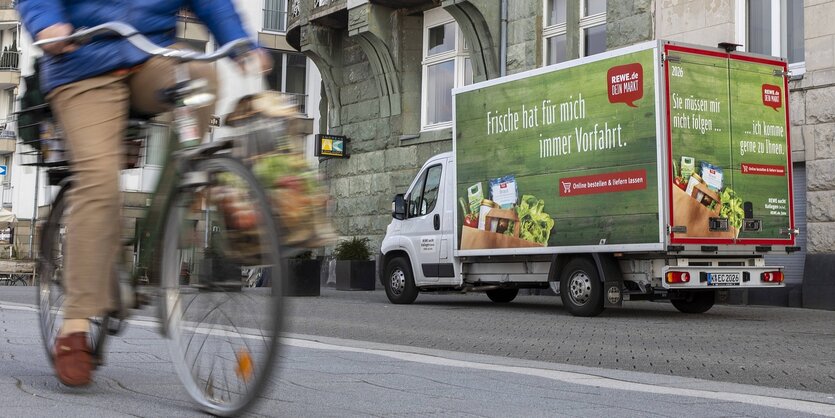 Ein Lieferwagen von Rewe fährt die Straße entlang