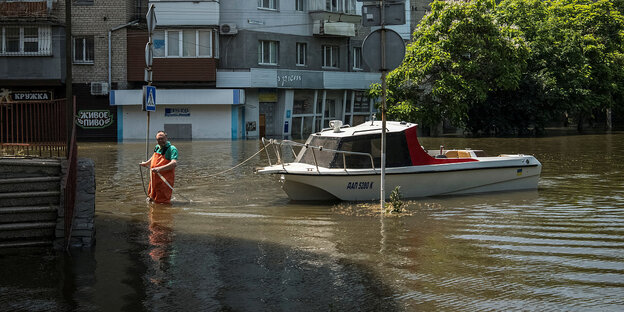 Ein Mann mit seinem Boot in einer überfluteten Straße