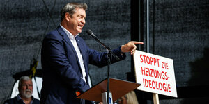 Markus Söder steht auf einer Bühne, vor ihm ist ein Schild mit der Aufschrift: Stoppt die Heizungsideologie