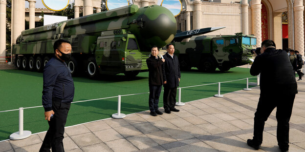 Besucher fotografieren sich in Peking vor ausgestellten Militärfahrzeiugen und Raketen
