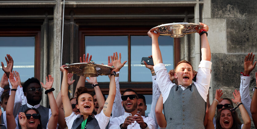 Bayerns Manuel Neuer und Lina Magull jubeln mit den Meisterschalen auf dem Rathaus-Balkon.