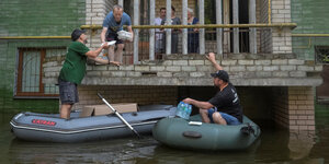Freiwillige versuchen An­woh­ne­r:in­nen aus ihren überfluteten Häusern zu holen