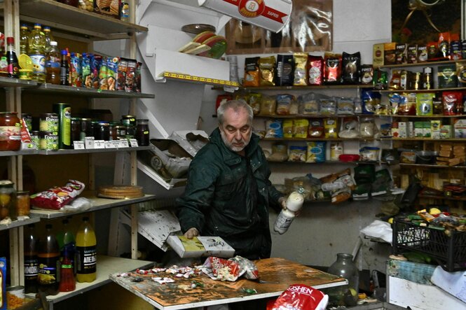 Oleksii, 60, räumt seinen Laden nach dem Hochwasser auf.