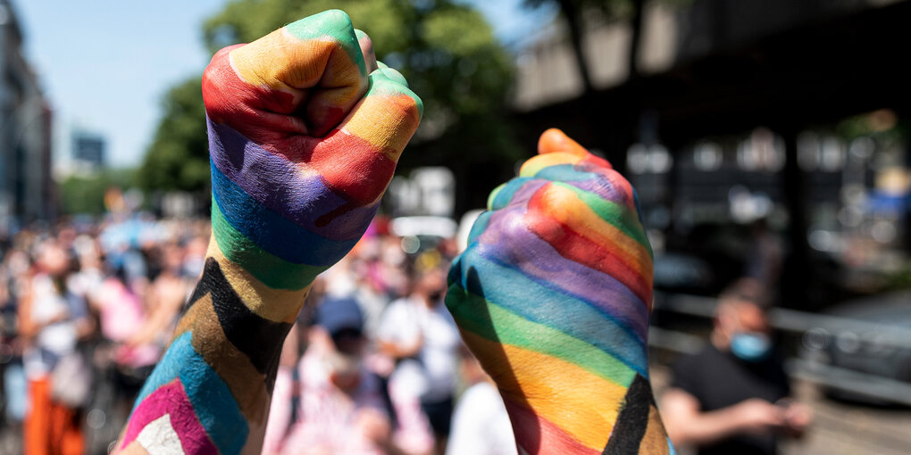 Zwei Teilnehmer der «Pride Berlin: Save our Community, Save our Pride» halten ihre Faust in die Höhe, die in Regenbogenfarbe angemalt sind.