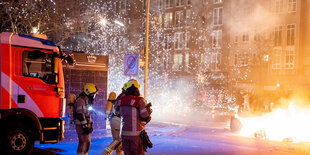 Randale in der Silvesternacht in Kreuzberg und Neukölln. Feuerwehrmänner löschen eine brennende Barrikade aus Mülltonnen und Mietrollern an der Kreuzung Sanderstraße / Kottbusser Damm Berlin