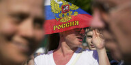 Eine Frau schütz sich mit Hilfe einer russischen Fahne vor der Sonne