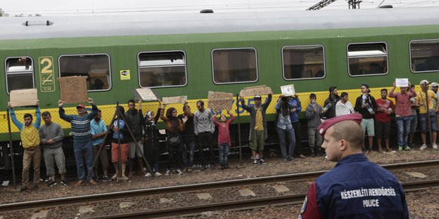 Menschen stehen mit Transparenten an einem Zug
