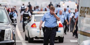 Ein Polizist reibt sich die Augen.