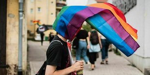 Jemand trägt eine Regenbobenfahne auf dem Kopf