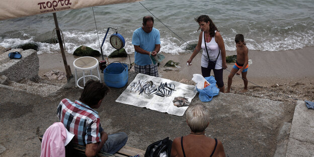 Ein Mann verkauft frischen Fisch an einem Strand bei Athen