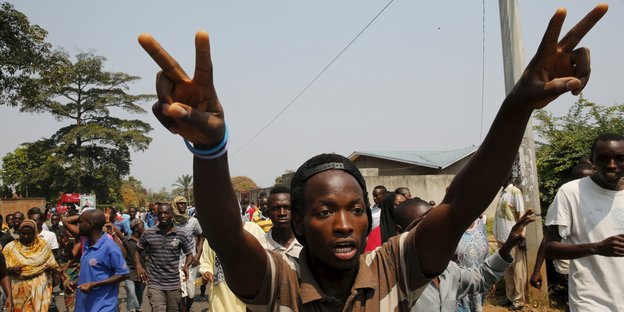 Ein junger Mann demonstriert in Burundi. Er reckt die Arme in den Himmel