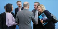 Bundeskanzler Olaf Scholz und Mitglieder der Bundesregierung stehen vor einer blauen Wand und geben sich die Hände
