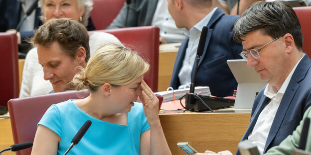 Katharina Schulze im Plenarsaal wendet den Kopf ab und fasst sich mit der Hand an die Stirn