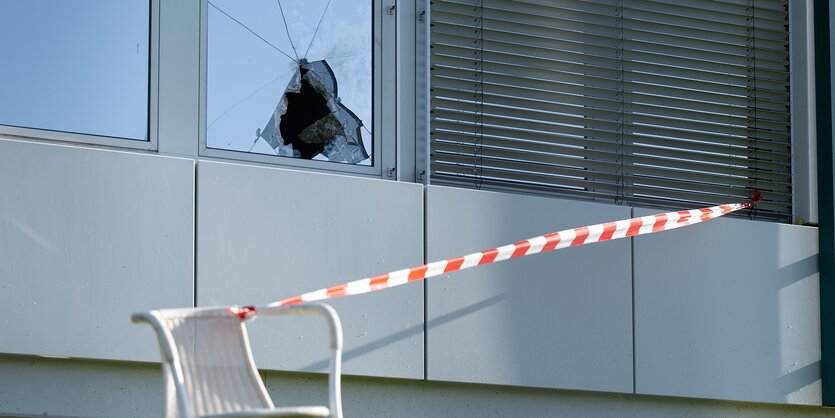 Eine zerborstene Scheibe und Absperrband vor einem Gebäude