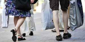 Personen mit vielen Einkaufstaschen laufen durch eine Einkaufsstraße