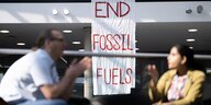 Menschen diskutieren. Im Hintergrund ein Banner mit der Schrift "End fossil fuels"