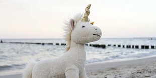 Ein Einhorn-Stofftier auf einem Strand