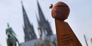 Rötliche Metallskulptur mit Kölner Dom im Hintergrund