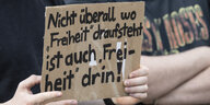 Teilnehmer eines Demonstrationszuges in Frankfurt/Main mit einem Schild: „Nicht überall wo Freiheit draufsteht ist auch Freiheit drin !“