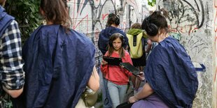 Menschen mit Kopfhörern und Tablets in enger Gasse